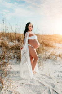 Maternity Photographer, a pregnant woman stands on the beach stands in a gown