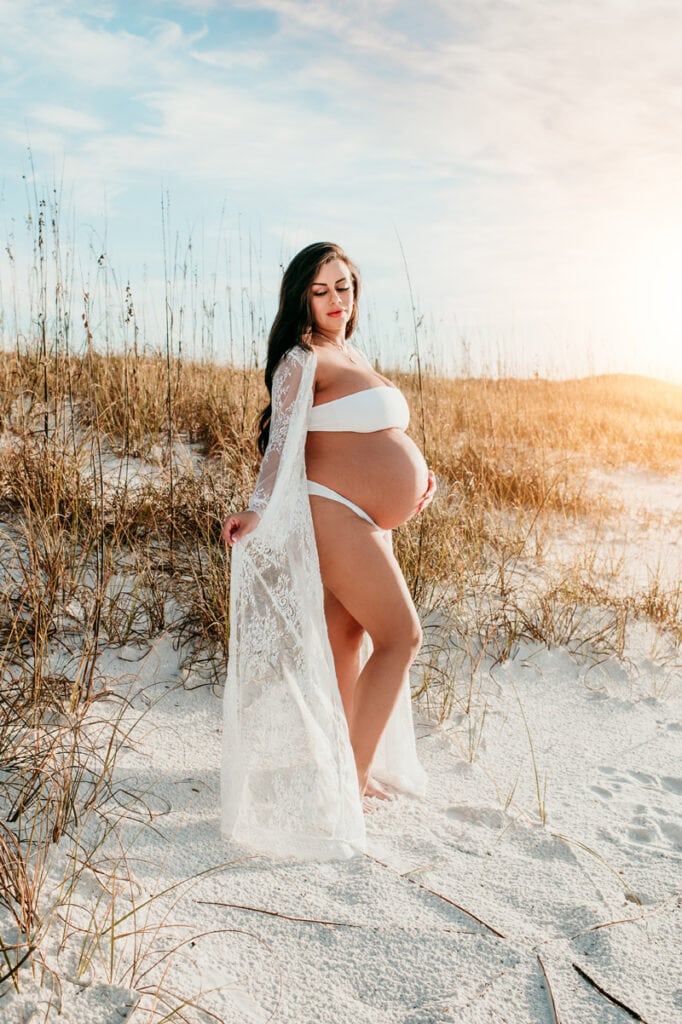 Maternity Photographer, a pregnant woman stands on the beach stands in a gown